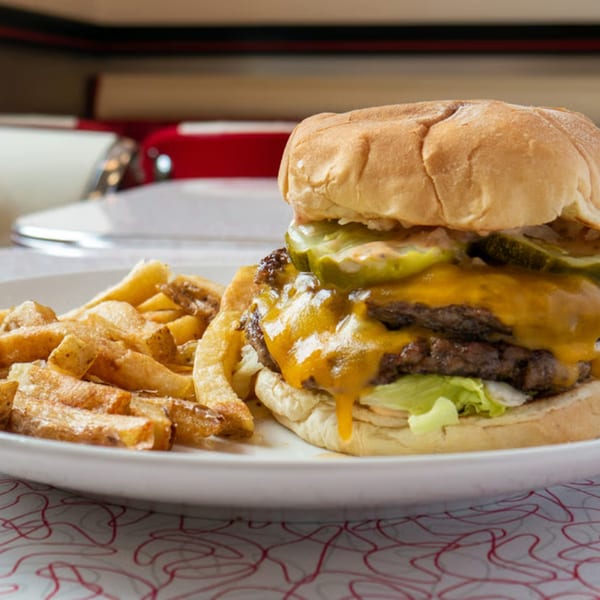Classic Burgers' double cheeseburger with melted cheese, pickles, lettuce, and a side of fries.