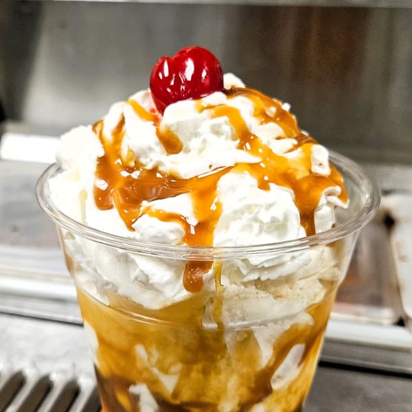 Classic Burgers' caramel milkshake with whipped cream, caramel drizzle, and a cherry on top.