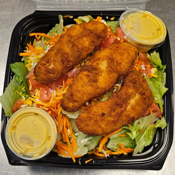 Classic Burgers' crispy chicken salad with lettuce, shredded carrots, cheese, tomatoes, and two dressing cups.