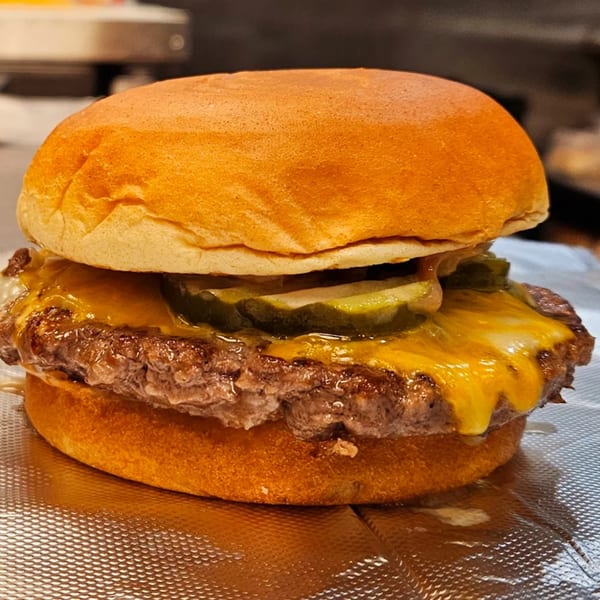 Classic Burgers' cheeseburger with melted cheese and pickles on a toasted bun.