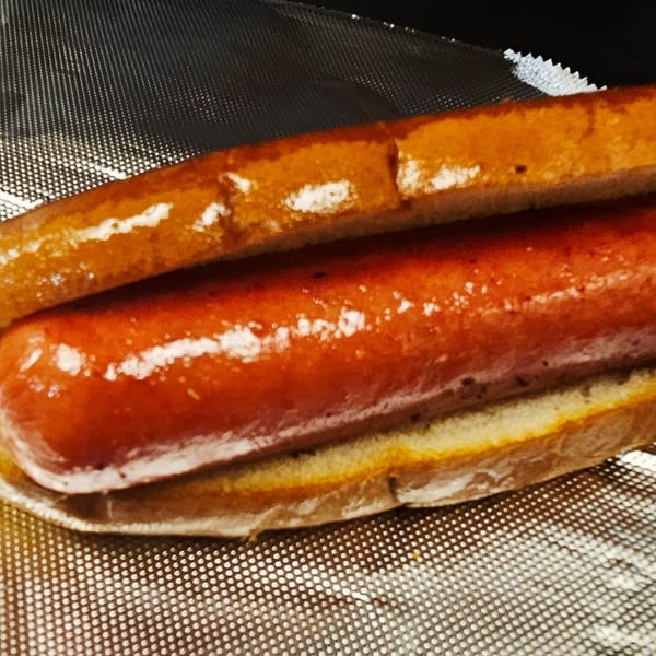A Classic Burgers hot dog in a bun, resting on a metallic surface.